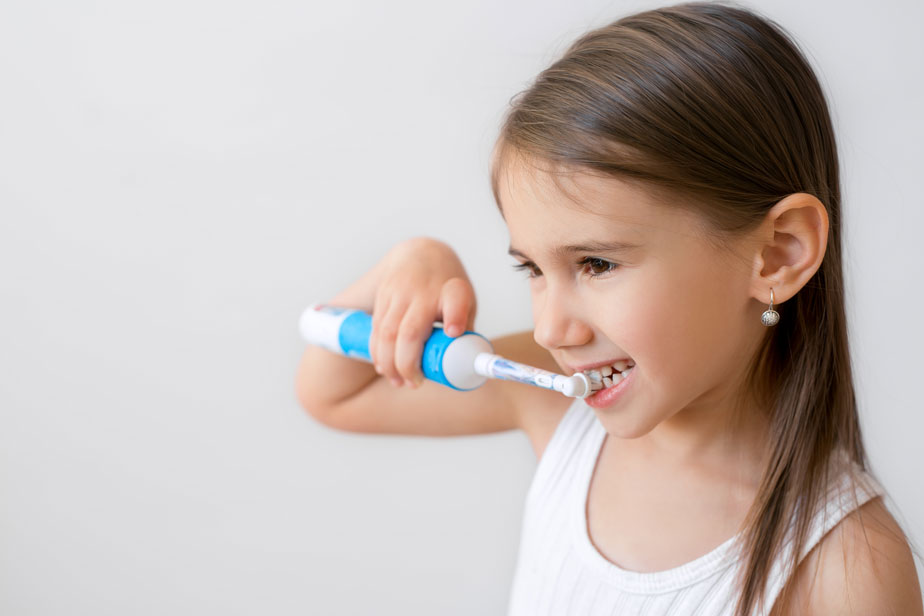 Bambina che lava i denti con lo spazzolino elettrico